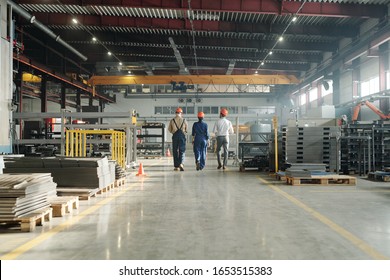 Rear view of three technicians or engineers of industrial plant in workwear leaving workshop at the end of working day - Shutterstock ID 1653515383