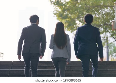 rear view of three young successful asian business people ascending steps - Shutterstock ID 1970898665