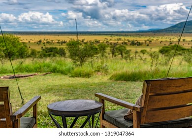 Rear View Of Timber Outdoor Chairs On The Verandah Of An Exclusive, Luxury Safari Tent Overlooking The Serengeti Grasslands. Selective Focus. African Landscape. Kiota Camp, Seronera Valley, Tanzania.