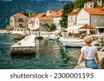 Rear view of a tourist woman looking at the small port of Perast, Kotor Bay, Montenegro