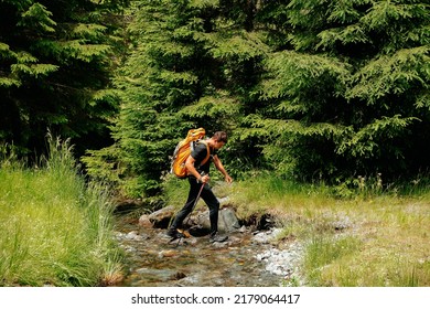 rear view of a tourist young man with a backpack travels through the forest near the river. young man equipped with tourist equipment hiking, lifestyle. active life mode, active rest