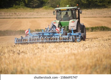 Rear View Of Tractor Ploughing Field Using Disc Plough