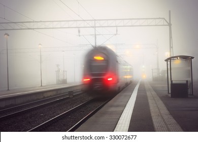 Rear View Of Train Leaving Station On Foggy Gloomy Day