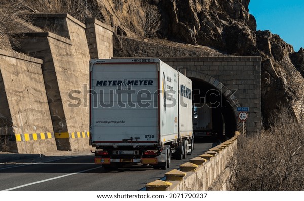 Rear view of truck belonging to the German company\
Meyer and Meyer on the mountain road, at the entrance to the\
tunnel. Semi truck carrying freights on the tunnel road. Orsova,\
November 9, 2021