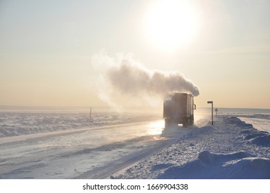 Rear View Of The Truck With The Steam From The Pipe, Driving On Ice Road On Lena River, During Beautiful Sunrise