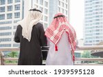 Rear view of two arab middle eastern standing outside in the city, two muslim business man waering traditional clothes standing outdoor city background