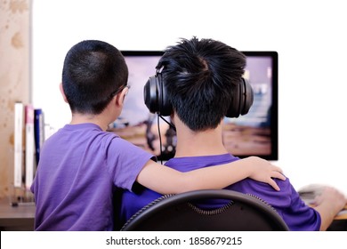 Rear View Of Two Brother Boys Playing Online Interactive Video Games Together With Friends In Front Of Computer Via Voice Chat. Kids Have Fun And Stay At Home Under Covid-19 Pandemic.