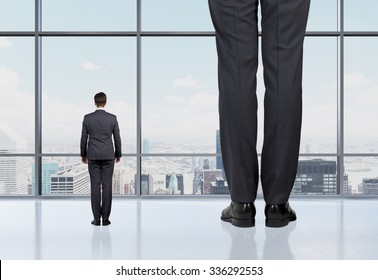 Rear view of two professionals in formal suites who stand in front of panoramic window with New York city view. The concept of professional consulting services.