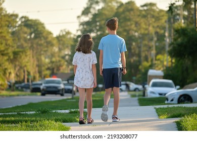 Rear view of two young teenage children, girl and boy, brother and sister walking together on rural street on bright sunny day. Vacation time concept - Powered by Shutterstock