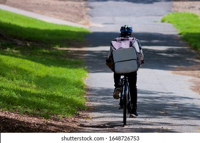 Rear View Of An Uber Eats Courier On A Bicycle In Brisbane. Uber Eats Is An American Online Food Ordering And Delivery Platform Launched By Uber