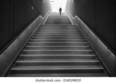 Rear view of an unrecognizable man walking up subway stairs into the light. - Shutterstock ID 2140198019
