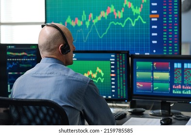 Rear view of unrecognizable mature Caucasian man wearing headphones monitoring stock trading stats - Shutterstock ID 2159785585
