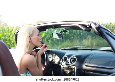 Rear view of woman applying lipstick in convertible - Powered by Shutterstock