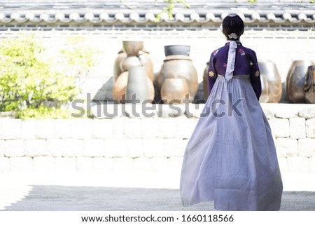 Rear view of woman in Hanbok standing at traditional Korean house
