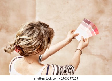 Rear View Of Woman Holding Paint Color Swatches In Unrenovated Room