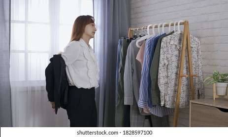 Rear View Woman Just Getting Off Work, Walking Into Bedroom, Taking Off Her Jacket And Hanging It On A Hanger. Shaking The Dust Off The Coat Before Hanging It On The Rack. Real Moments