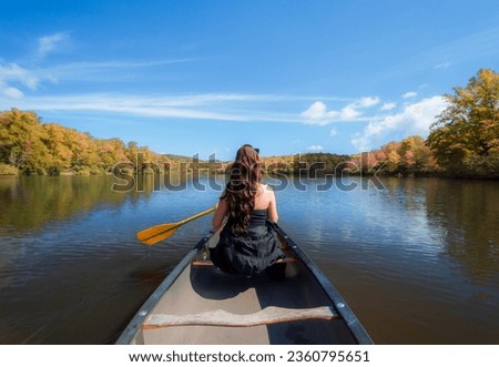 Rear view of woman paddling the canoe on  Julain Price lake on Blue ridge Parkway, North Carolina, USA.
