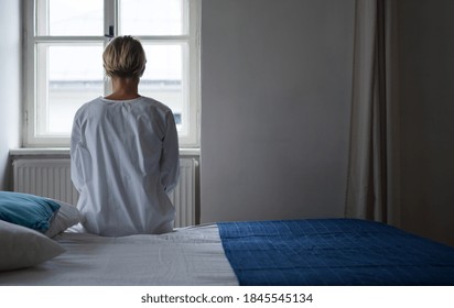 Rear view of woman patient sitting on bed in hospital feeling stressed, mental health and coronavirus concept. - Shutterstock ID 1845545134