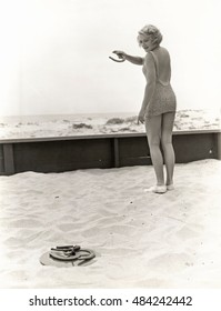 Rear View Of Woman Playing Horseshoes At The Beach