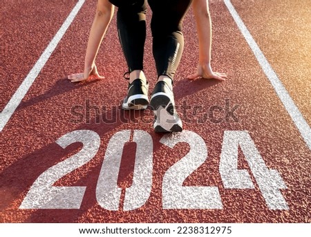 Rear view of a woman preparing to start on an athletics track engraved with the year 2024 Foto stock © 