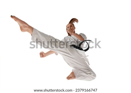 Rear view. Woman professional karate fighter jumping and performing kick in action isolated over white background. Concept of sport, recreation, art, hobby, culture. Copy space for ad, text.