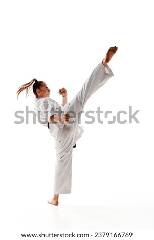 Rear view. Woman professional karate fighter performing kick in action isolated over white background. Concept of sport, recreation, art, hobby, culture. Copy space for ad, text.
