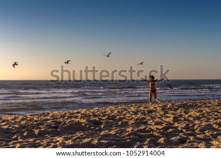 Rear view of a woman in the red swimsuit running on the beach on the Atlantic Ocean in Portugal