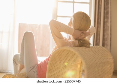 Rear view of woman relaxing on chair at home