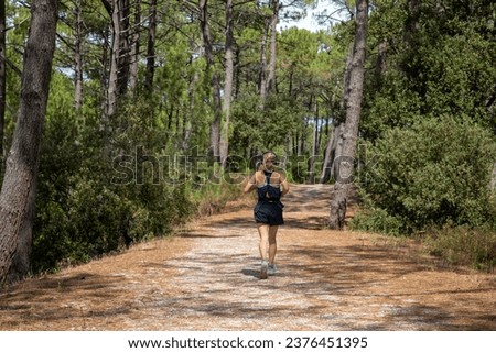 Rear view of woman running alone in pine forest pathway environment listen music jogger girl