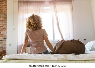 Rear view of woman sitting on bed in youth hostel