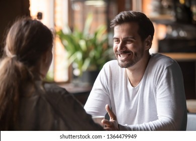 Rear view woman sitting at table in cafe with handsome smiling man, people spends time at meeting searching for soul mate, male telling about himself making good first impression, speed dating concept