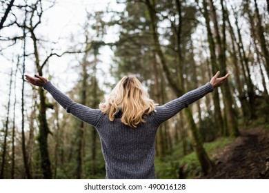 Rear view of woman standing with arms outstretched in forest - Shutterstock ID 490016128