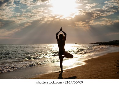 Rear View Of A Woman Standing In A Tree Position On The Seashore. She's Watching The Sun. Inner Harmony And Self Body Care.