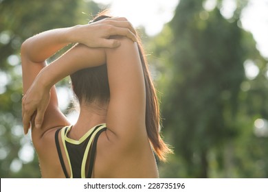 Rear view of woman stretching her arm and shoulder 