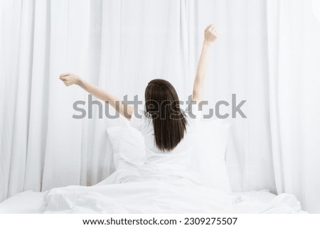 Rear view of a woman stretching her hands after wake up in the morning.