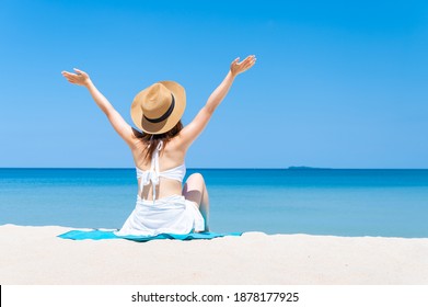 Rear view of  woman wearing sun hat and white bikini spends vacation at the beach on a white sand. summer beach concept - Powered by Shutterstock