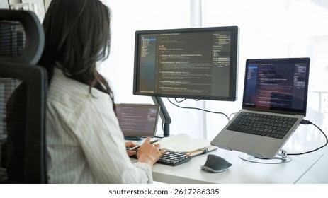 Rear view of a woman working on programming code with professional dual-monitor setup in bright workspace. - Powered by Shutterstock - Get 15% off with code: PIKWIZARD15