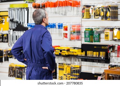 Rear view of worker with hands on hip standing in hardware store