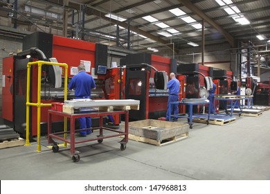 Rear view of workers at manufacture workshop operating machines