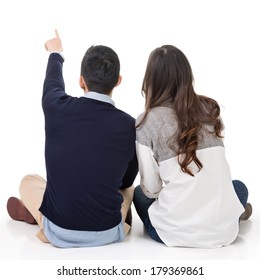 Rear view of young Asian couple sit on ground back and point somewhere, full length portrait isolated on studio white background.