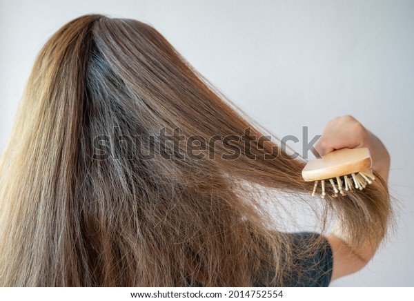 Rear view of young Asian woman brushing her thick\
hair. Thick hair technically refers to the width of a single strand\
of hair, whereas hair density refers to the number of strands on\
your head.
