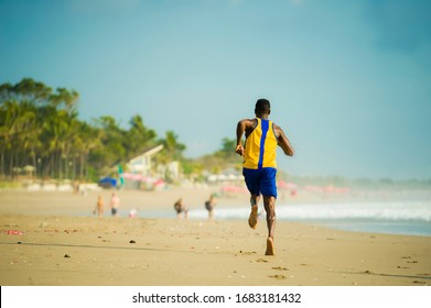 rear view of young athletic and fit african american sport man doing running workout on sunset at the beach training hard jogging barefoot on sand in healthy lifestyle concept