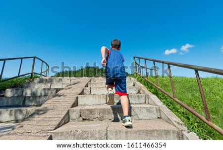 Rear view of young boy running up on steps.