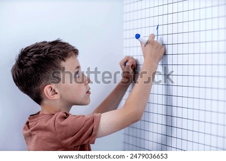 Rear view of young boy solving math problems on white board