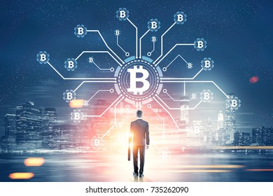 Rear view of a young businessman holding a suitcase looking at a bitcoin network hologram in a night city sky. Toned image double exposure. Elements of this image furnished by NASA - Shutterstock ID 735262090