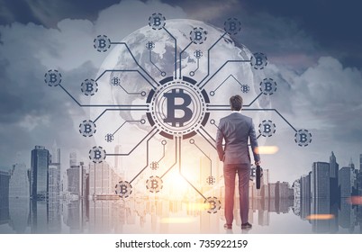Rear view of a young businessman holding a suitcase looking at a bitcoin network hologram in a morning city sky. Toned image double exposure. Elements of this image furnished by NASA - Shutterstock ID 735922159
