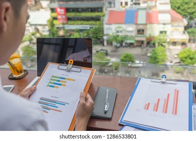 Rear View Of Young Businessman Reading Reports