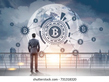 Rear view of a young businessman in a suit looking at a bitcoin HUD hologram in a morning city sky. Toned image double exposure. Elements of this image furnished by NASA - Shutterstock ID 731318320