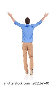 Rear View Of A Young Casual Man Holding His Hand Up, Celebrating A Victory.