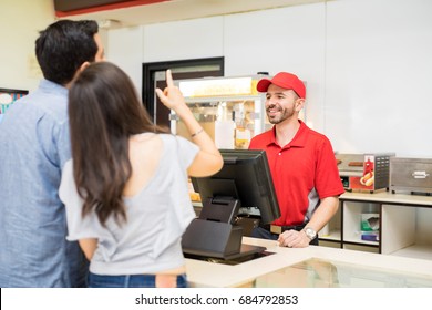 Rear View Of A Young Couple Deciding What To Buy In A Concession Stand At The Movie Theater